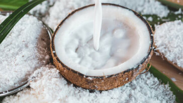 Pouring Fresh Coconut Milk And Coconut Fruit Ingredient On Wooden Table