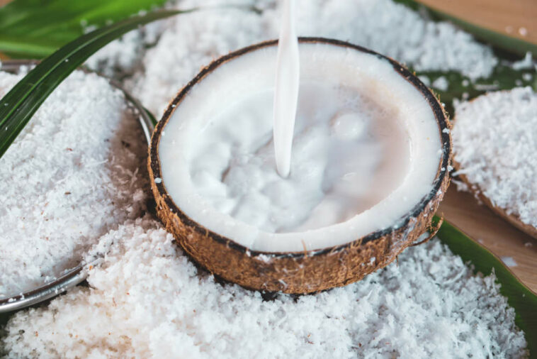 Pouring Fresh Coconut Milk And Coconut Fruit Ingredient On Wooden Table